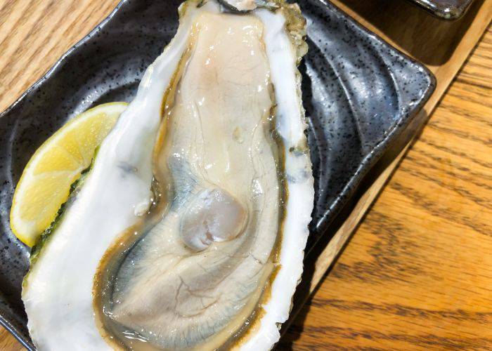 Shucked oyster with a slice of lemon on the side at Nishiki Market