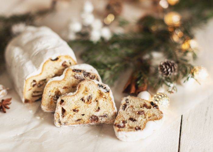 Stollen bread cut into several slices near a festive Christmas tree branch