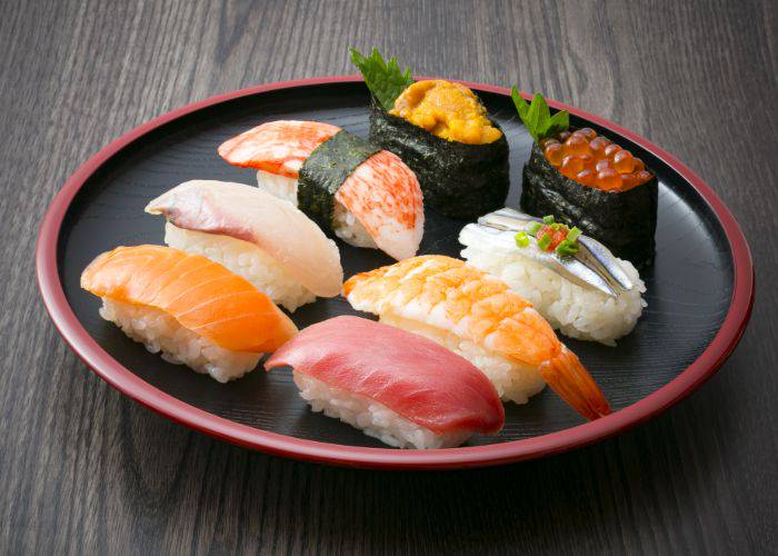 A plate of various types of nigiri and gunkan maki sushi