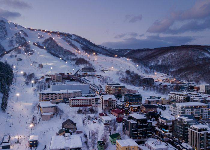 A glowing Niseko ski resort beginning to light up against the evening sky.