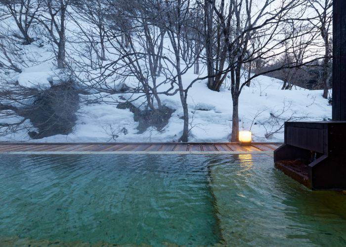 A steamy onsen hot spring set against a snow-covered landscape.