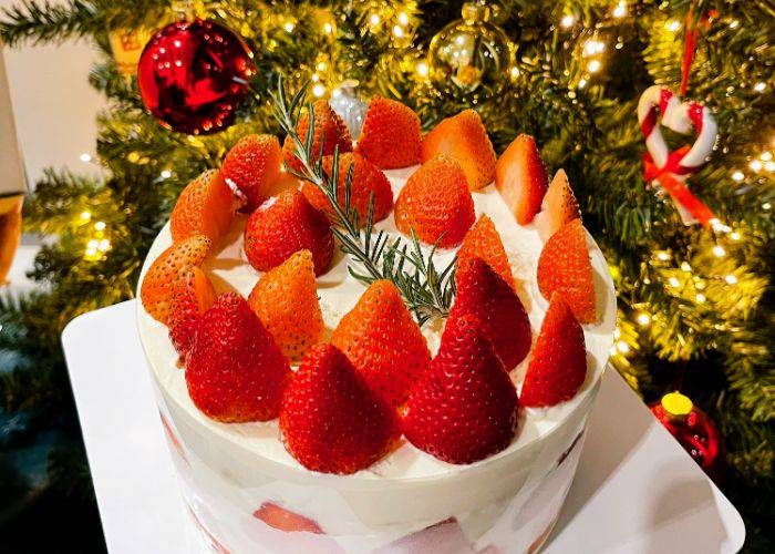 Strawberry shortcake set against a vibrant Christmas tree in Japan.