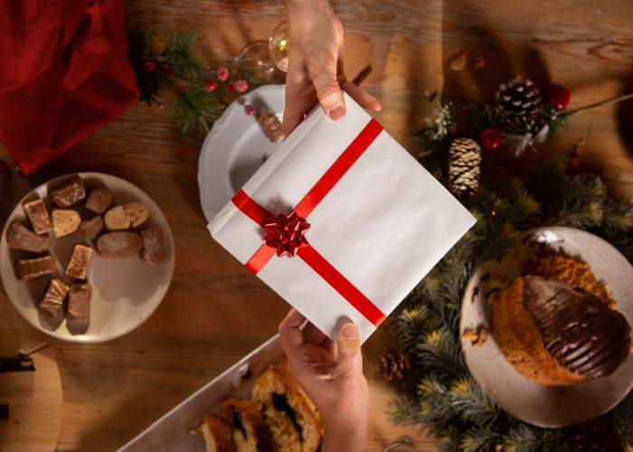 Someone passing a wrapped Christmas present over a table.