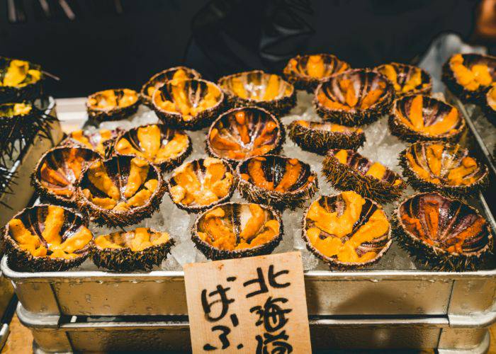 Uni cracked open and sitting on a bed of ice at a market in Japan