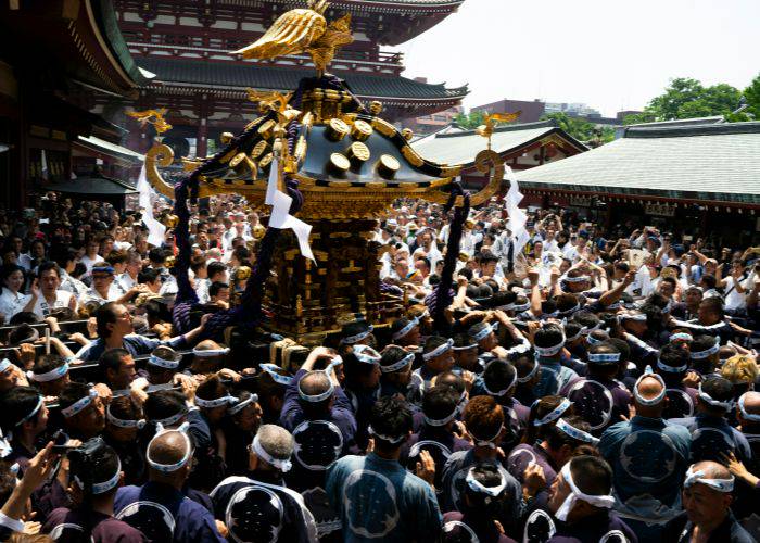 A crowd of people carrying a large portable shrine at Sanja Matsuri.