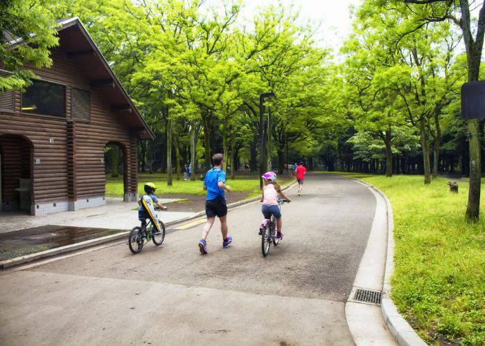 A family cycling through the lush nature of Yoyogi Park.