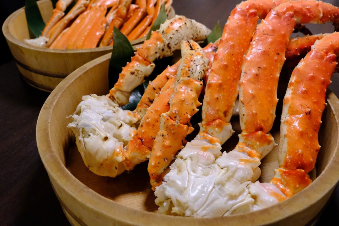 Fresh king crab legs served in wooden bowls, ready for a seafood feast.