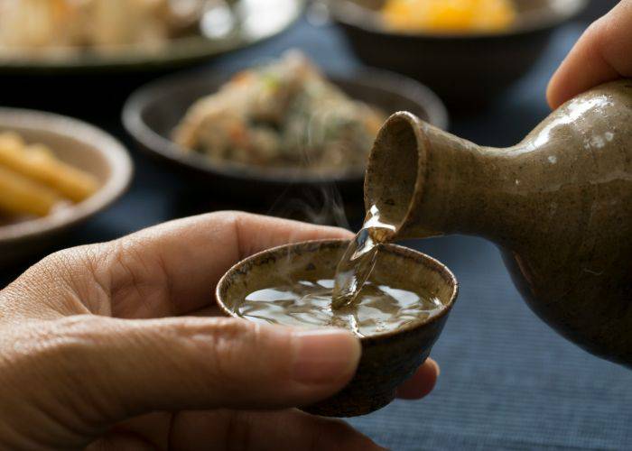 Someone pouring a cup of hot sake.