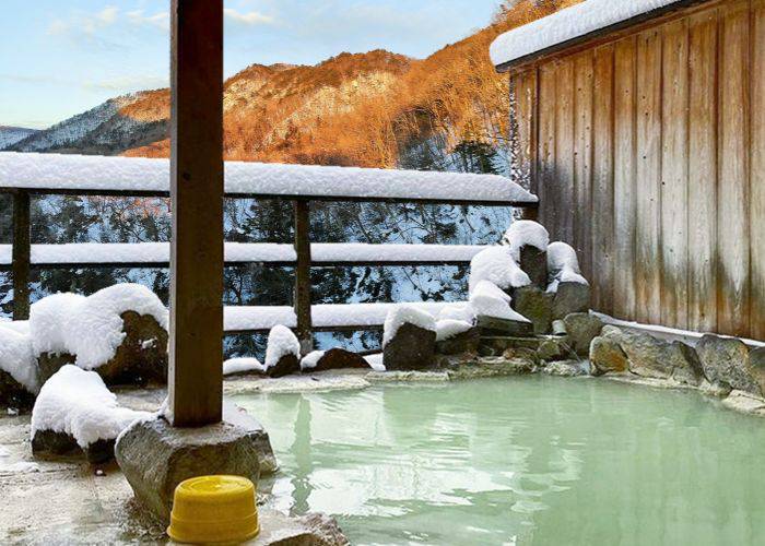 A tempting onsen hot spring surrounded by snow-topped scenery.