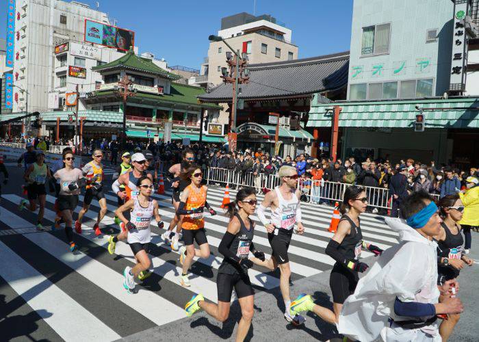 People running past a traditional Japanese building in the Tokyo Marathon.