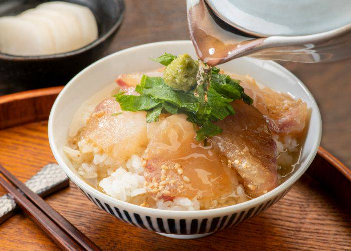 A bowl of sea bream tai-chazuke topped with wasabi and tea being poured on top