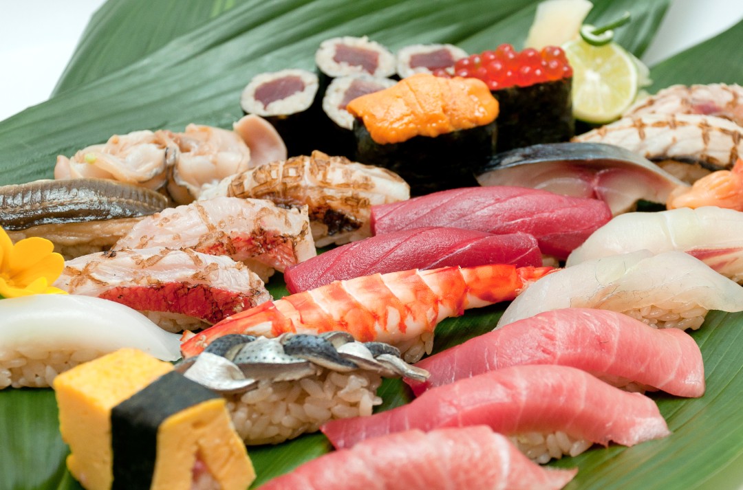 Assorted sushi platter with nigiri, sashimi, and rolls on a leaf