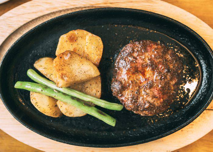 A griddle like plate of Japanese hamburg steak with potatoes and green beans