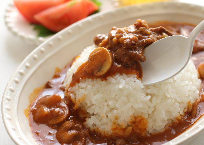 A spoon digging into a plate of hayashi rice