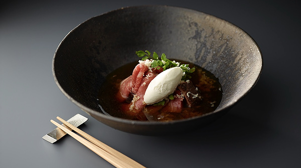 Elegant beef dish with creamy topping in a dark ceramic bowl