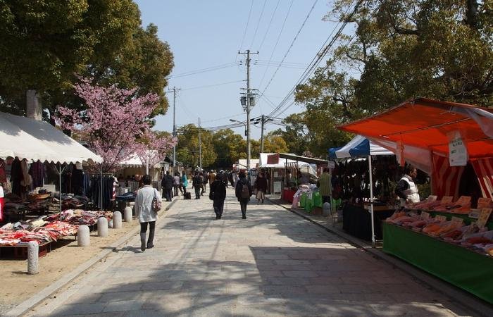 Spring at Shi-Tennoji Temple Market, sakura blooming in the background as people peruse various street stalls