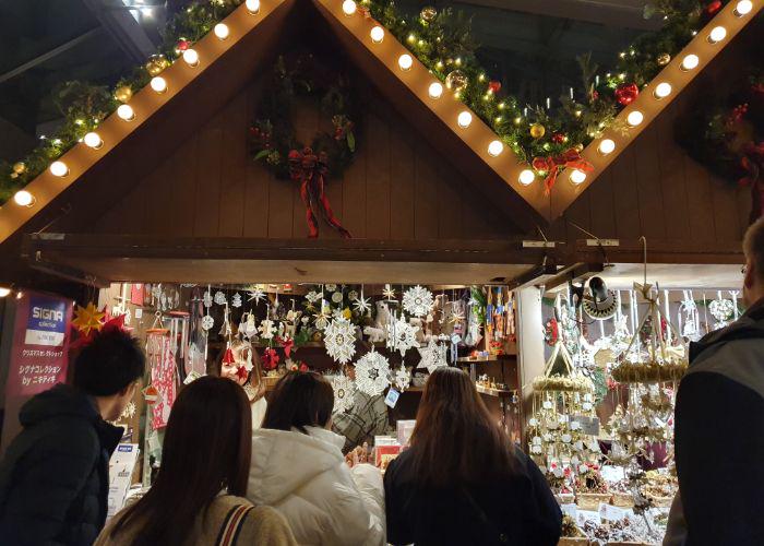 A line of people looking at the Christmas ornaments that are on sale at the Christmas Market