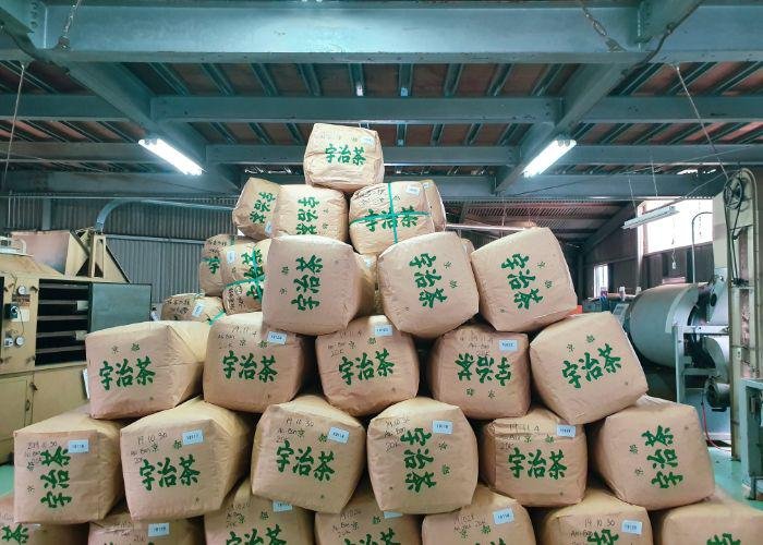 Inside the Obubu Tea Factory where there are brown packages stacked on top of each other in a diagonal shape