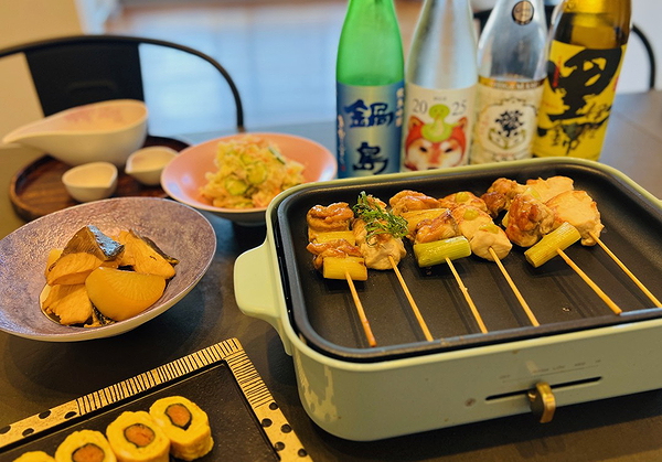 Japanese yakitori grill set with sake and side dishes on a table