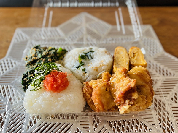 Japanese bento box with onigiri, spinach, tamagoyaki, and fried chicken