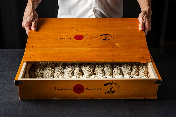 Chef opening wooden box of fresh handmade soba noodles