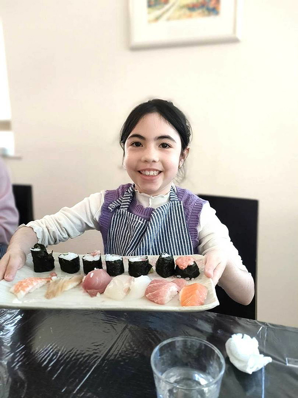 Child happily showcasing homemade sushi platter