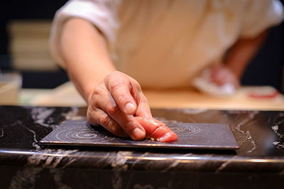 Chef skillfully preparing fresh sushi on a marble counter
