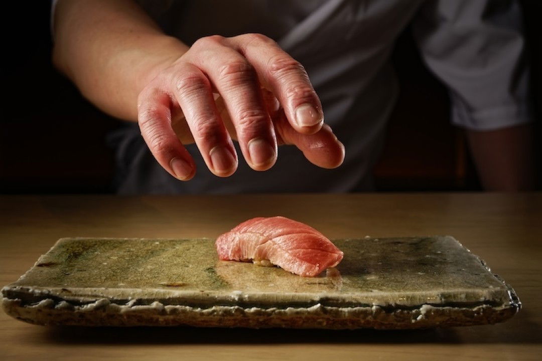 Chef places sushi on stone plate in gourmet restaurant