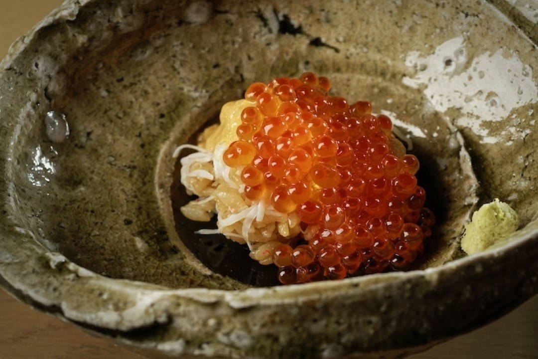 Gourmet seafood dish with vibrant salmon roe in ceramic bowl