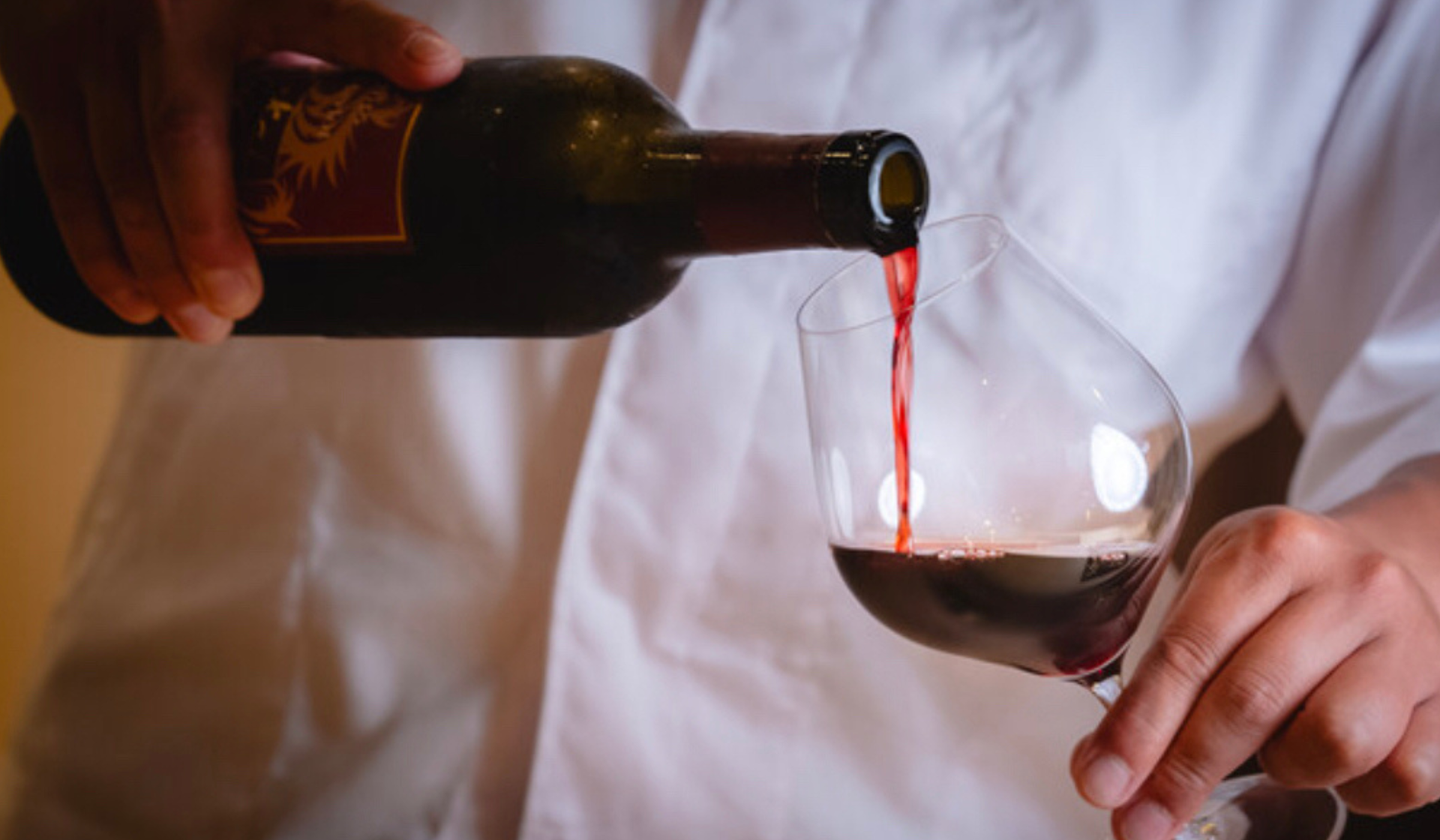 Sommelier pouring red wine into a glass at fine dining setting