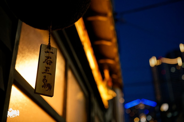 Traditional Japanese restaurant sign glowing at dusk in urban setting