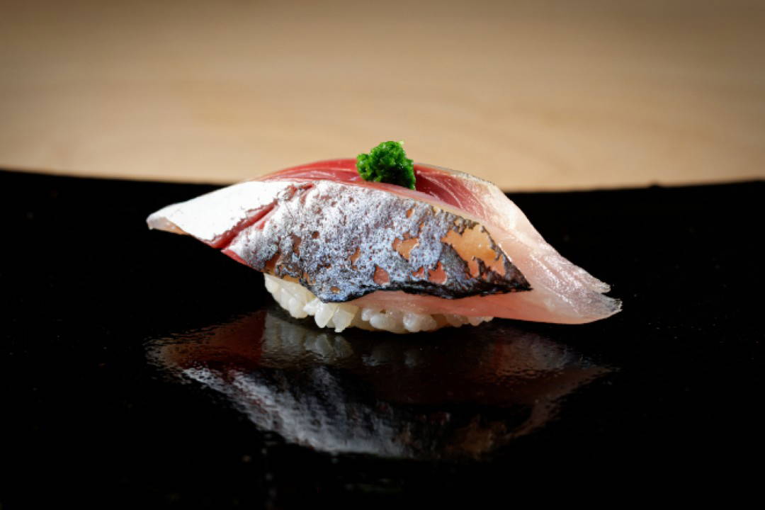 Elegant mackerel sushi on black plate at upscale Tokyo restaurant