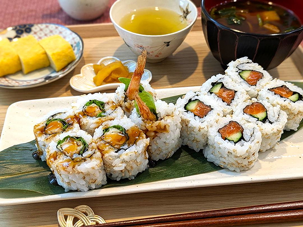 Delicious sushi rolls with green tea and soup on a wooden table