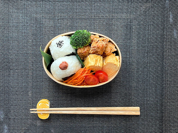 Japanese bento box with onigiri, karaage, and vegetables