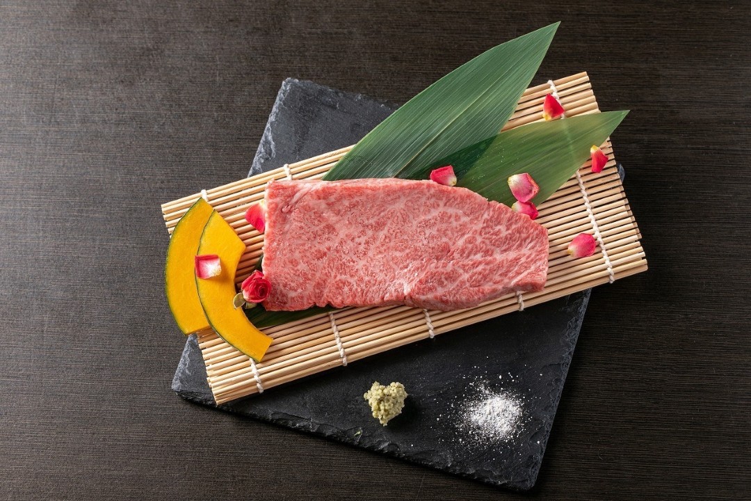 Premium wagyu beef slice with garnish on bamboo mat