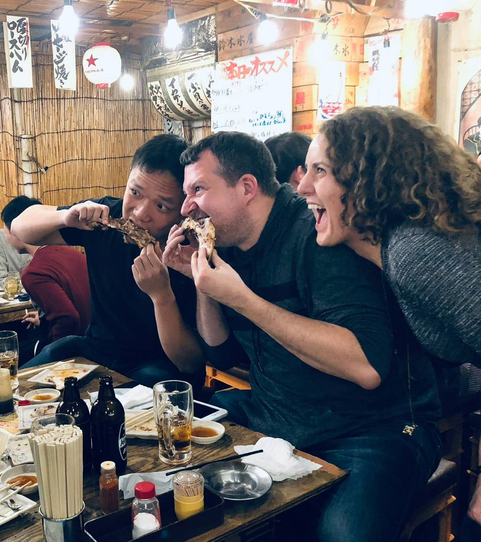 Friends enjoying grilled food at a lively Japanese izakaya