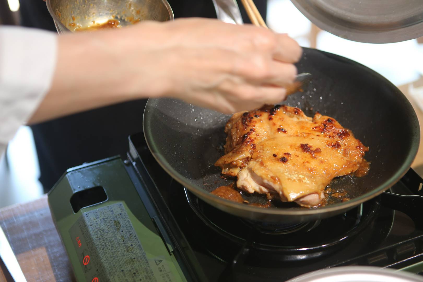 Chef skillfully cooking glazed meat in a pan