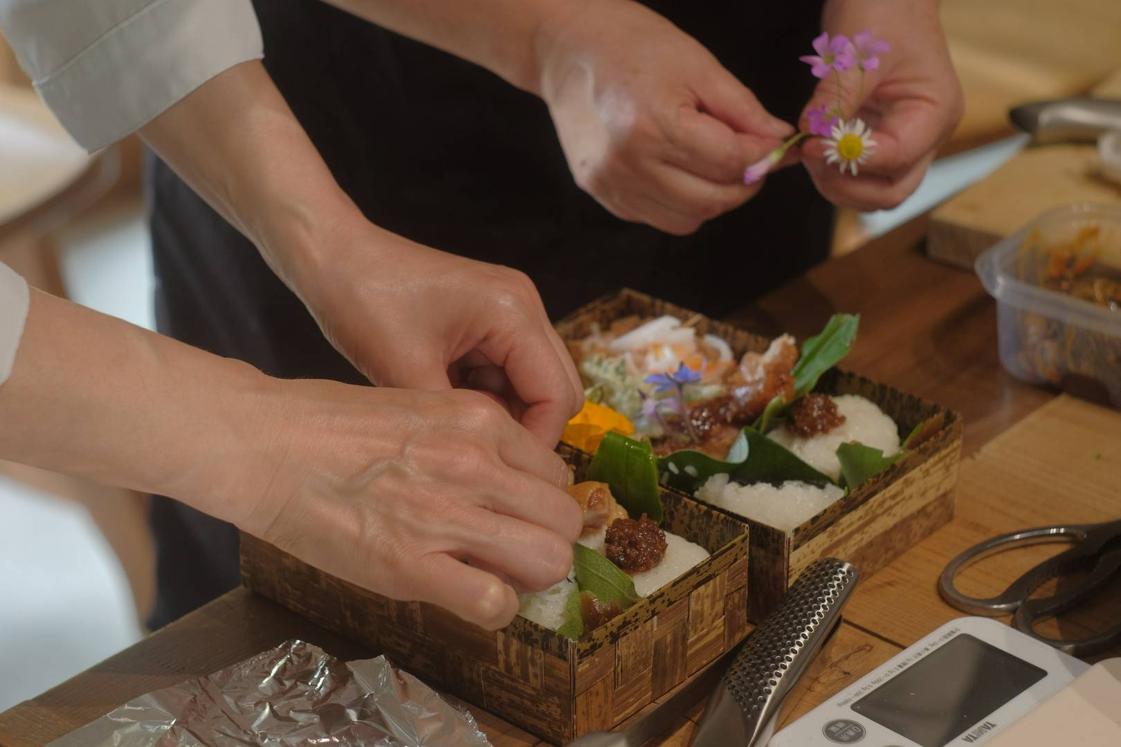 Chefs preparing elegant bento boxes with fresh ingredients