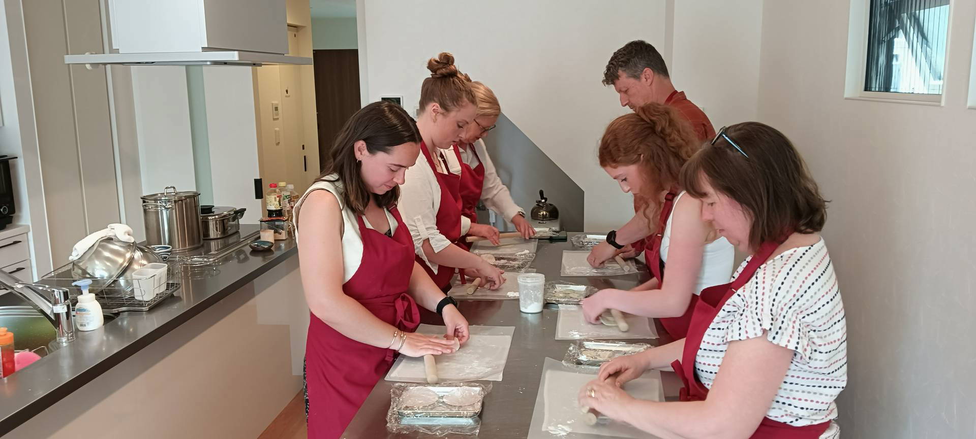 Cooking class participants wrapping ingredients in kitchen