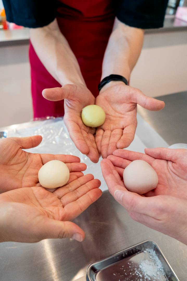 Hands holding freshly made mochi balls during a cooking class