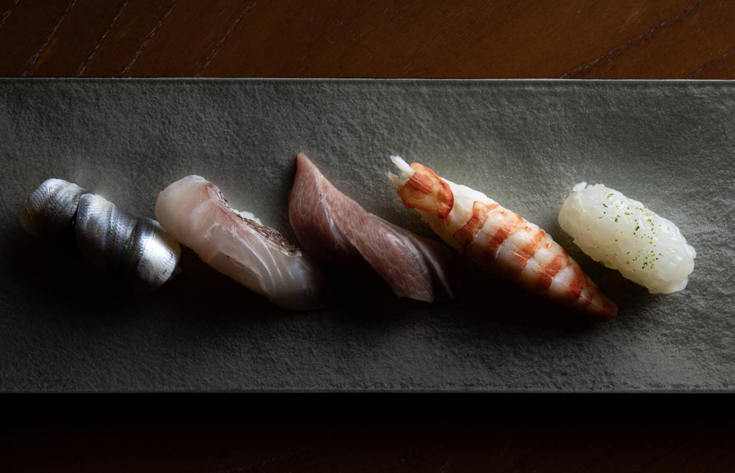 Assorted sushi nigiri on a stone plate in elegant restaurant setting