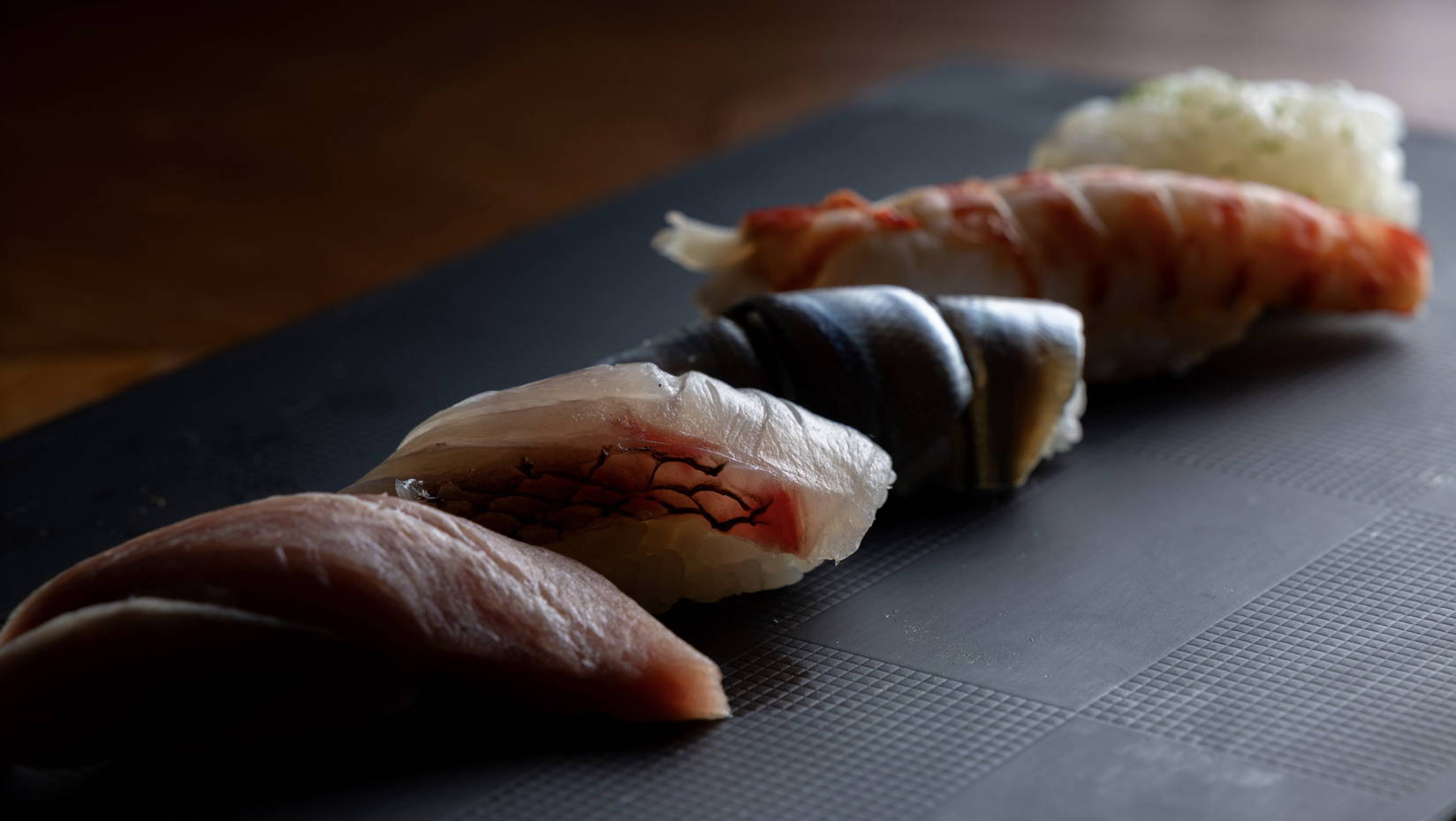 Assorted sushi nigiri on a sleek black platter