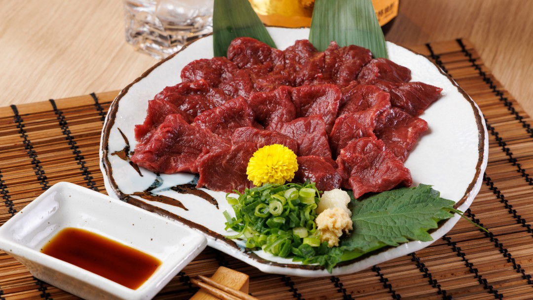 Delicious sashimi platter with fresh garnishes on a traditional mat.