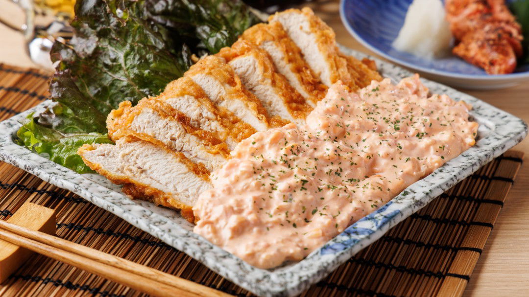 Crispy chicken katsu with creamy sauce on a decorative plate