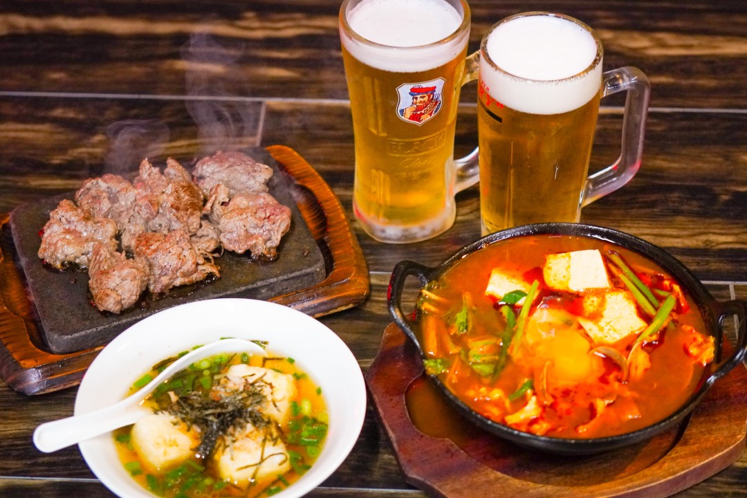 Delicious course menu with sizzling beef, ramen, kimchi stew, and draft beer