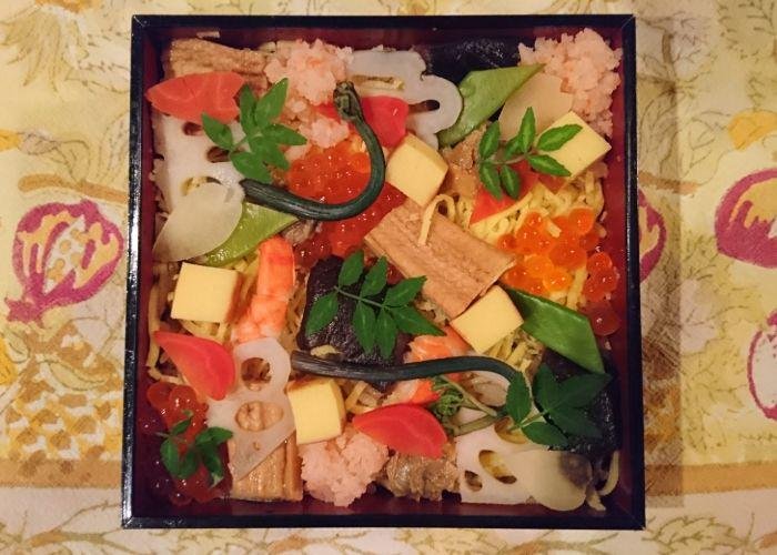 A celebratory box of chirashi-zushi that has prawns and vegetables on top of sushi rice 
