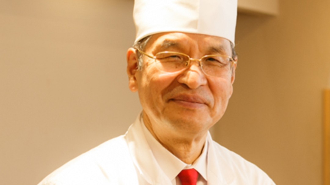 Experienced chef in uniform smiling warmly in restaurant kitchen