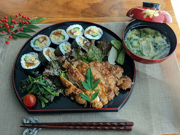 Japanese meal with sushi, miso soup, and chicken on decorative plate