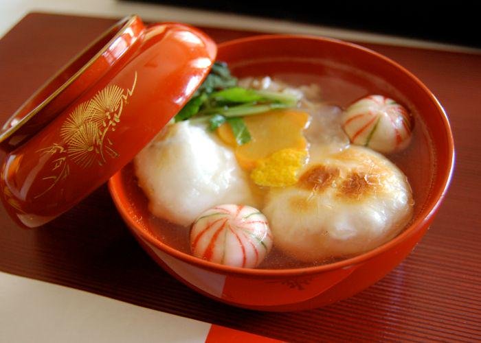A red bowl of ozoni soup that has mochi in