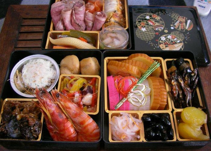 A table full of osechi ryori japanese food eaten at new year such as prawn, rice and vegetables